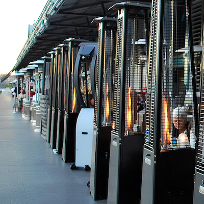 Outdoor seating at a restaurant lined with propane-powered heaters.